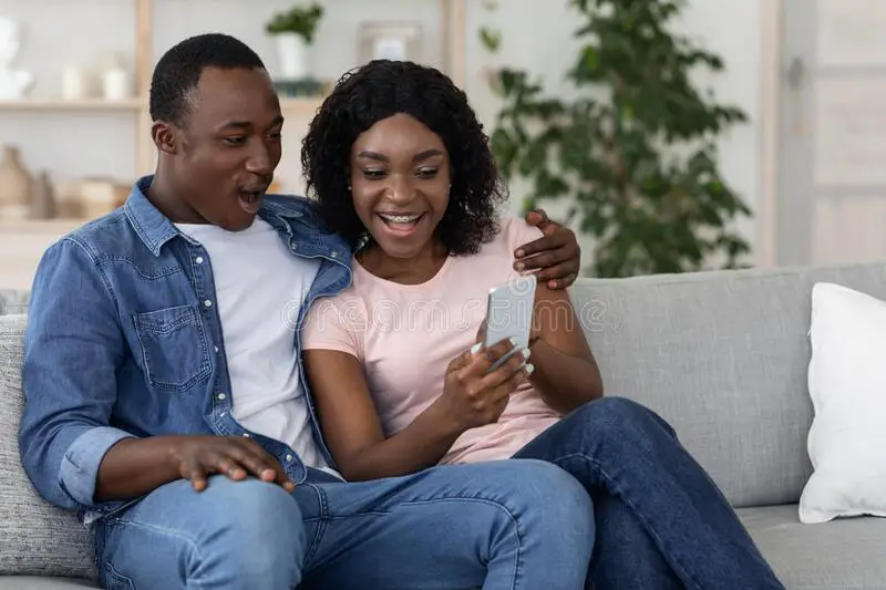 happy-black-wife-showing-her-husband-photos-smartphone-happy-black-wife-showing-her-husband-photos-smartphone-sitting-198344512